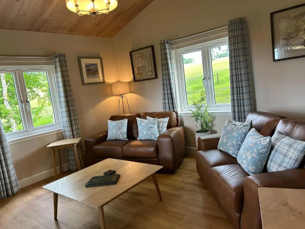 a living room with a couch and a table at Breckland Lodge 3 with Hot Tub in Belladrum