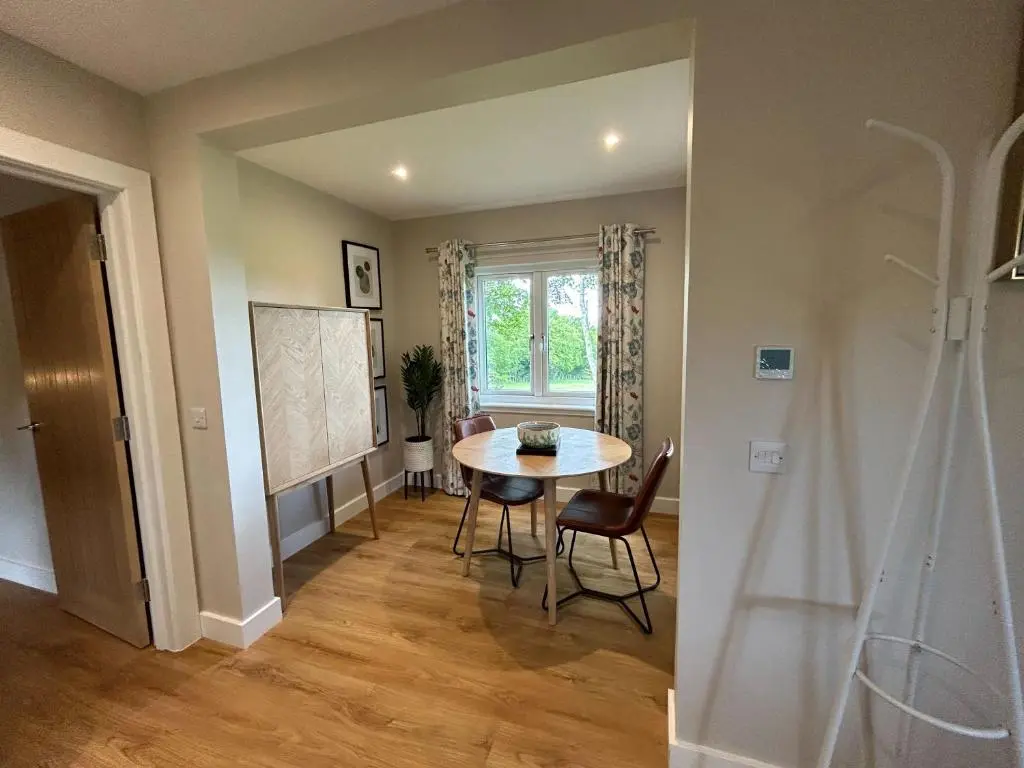 a dining room with a table and a window at Breckland Lodge 3 with Hot Tub in Belladrum