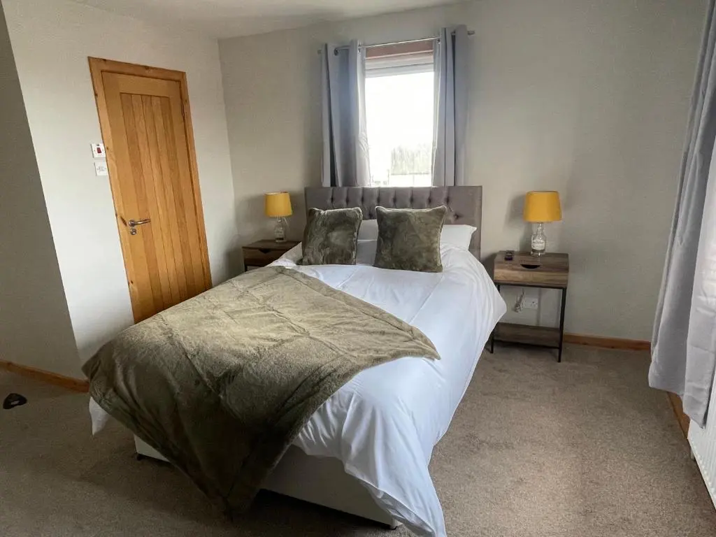 a bedroom with a bed with white sheets and a window at Impala Guest House in Wick