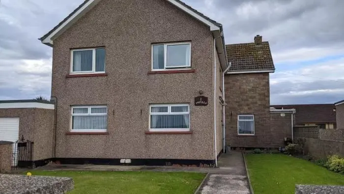 a brown brick house with windows and a yard at Impala Guest House in Wick