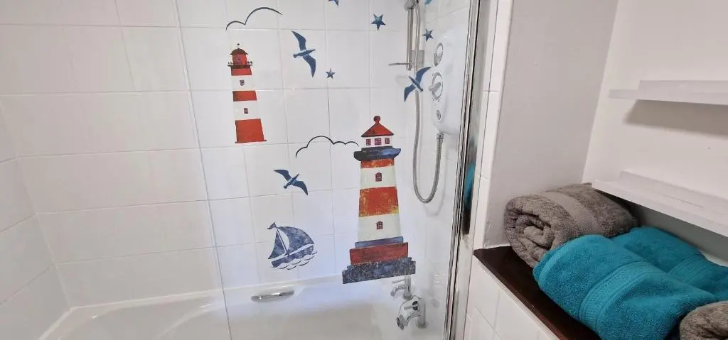 a bathroom with a shower with a mural of lighthouse at Colin Young Place in Nairn
