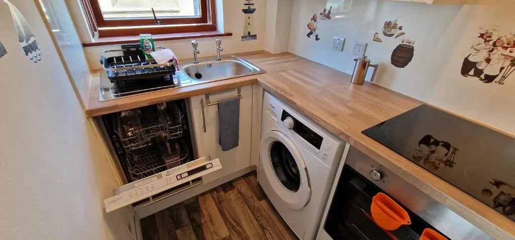 a kitchen with a sink and a washing machine at Colin Young Place in Nairn