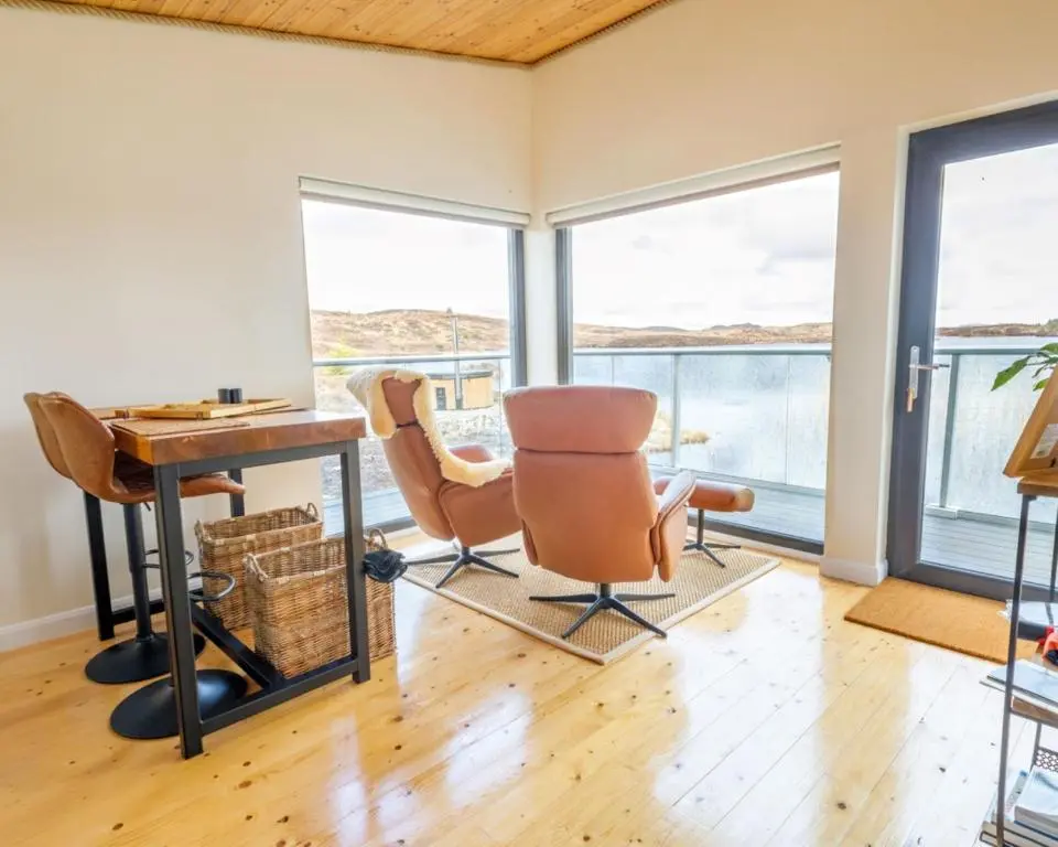 a room with a desk and chairs and windows at The Boathouse in Tomich