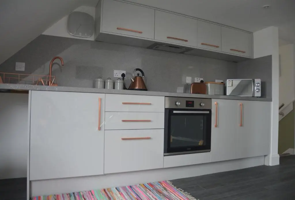 a kitchen with white cabinets and a stove at St Duthus Hotel Apartment in Tain