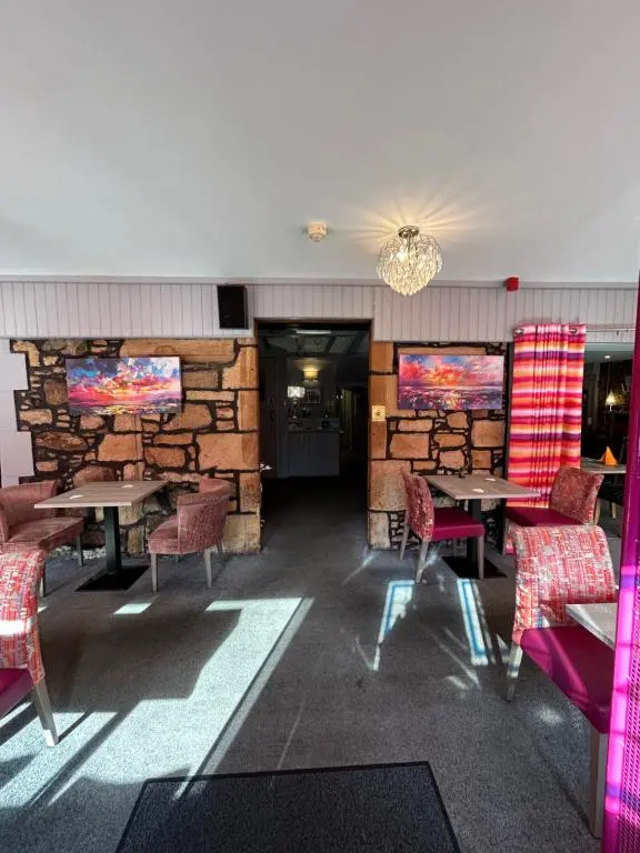 a restaurant with tables and chairs and a stone wall at St Duthus Hotel Apartment in Tain