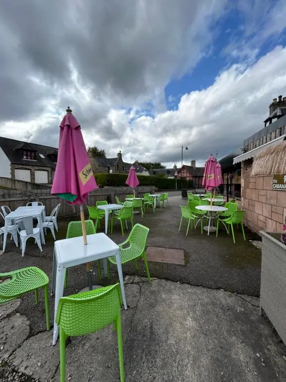 a group of tables and chairs with pink umbrellas at St Duthus Hotel Apartment in Tain