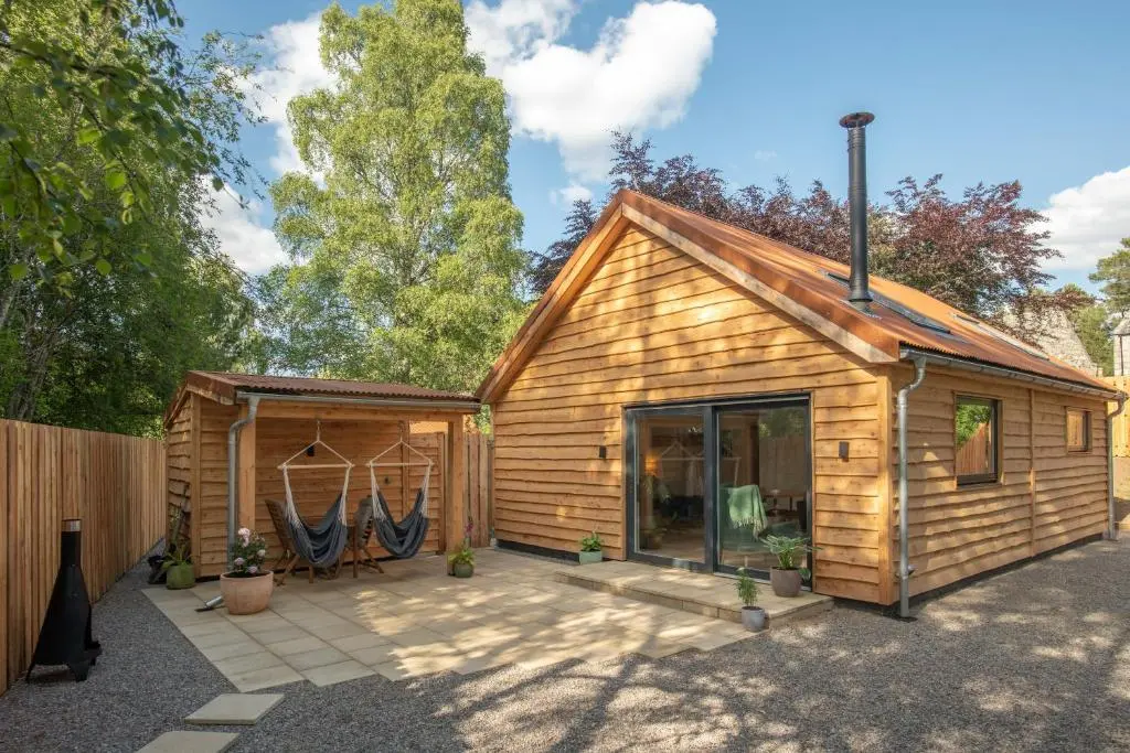 a wooden cabin with a patio in front of it at Arbor Nethy Bothy in Cairngorms National Park in Nethy Bridge