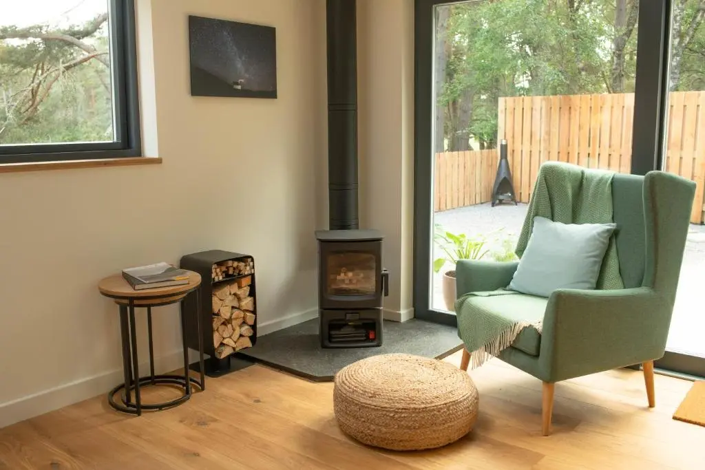 a living room with a chair and a wood stove at Arbor Nethy Bothy in Cairngorms National Park in Nethy Bridge