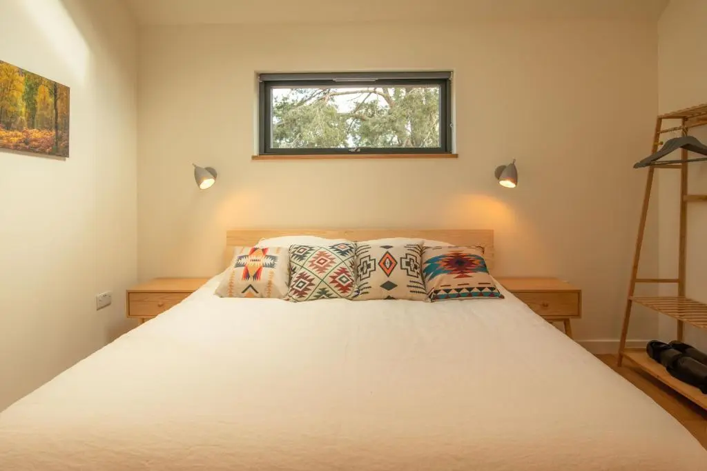 a bedroom with a white bed with two pillows at Arbor Nethy Bothy in Cairngorms National Park in Nethy Bridge