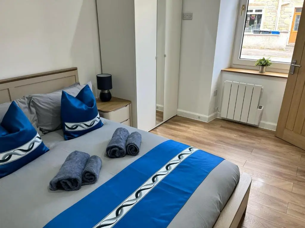 a bedroom with a bed with blue sheets and blue pillows at 51 Innes Street Apartment in Inverness