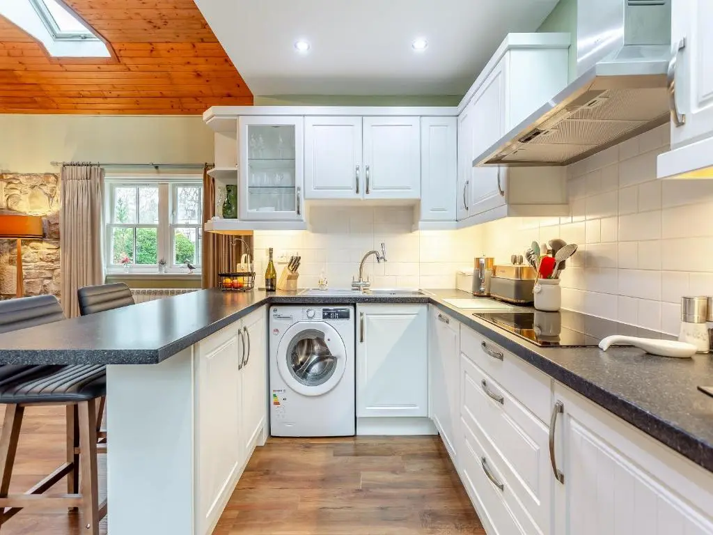 a kitchen with white cabinets and a dishwasher at The Bothy in Lochend