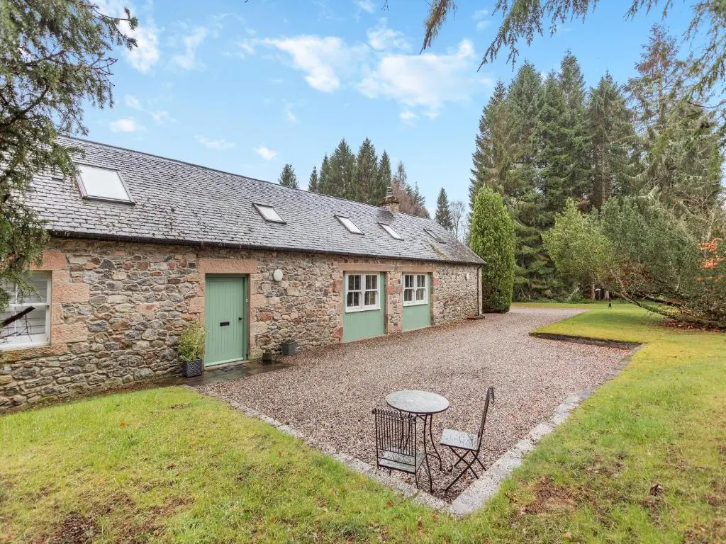 a stone house with a table and chairs in the yard at The Bothy in Lochend