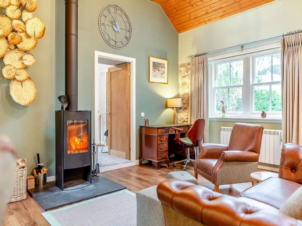 a living room with a fireplace and a clock on the wall at The Bothy in Lochend