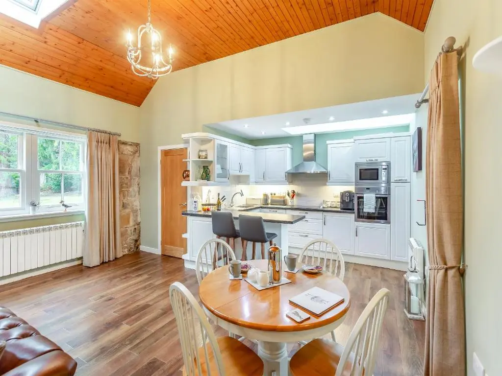a kitchen and dining room with a table and chairs at The Bothy in Lochend