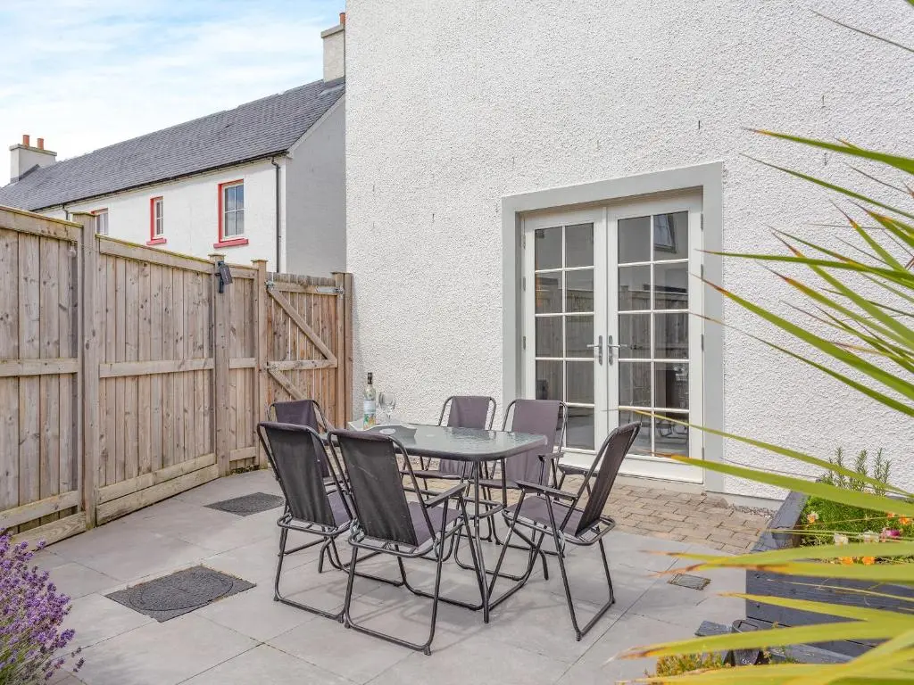 a patio with a table and chairs and a fence at One The Loan in Croy