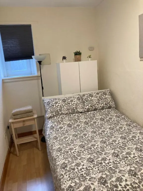 a small bedroom with a bed and a table at 2 Bed Central Ness Apart - May Court in Inverness