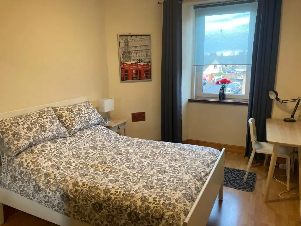 a bedroom with a bed and a desk and a window at 2 Bed Central Ness Apart - May Court in Inverness