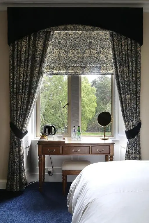 a bedroom with a bed and a window with a desk at Carnach House in Nairn