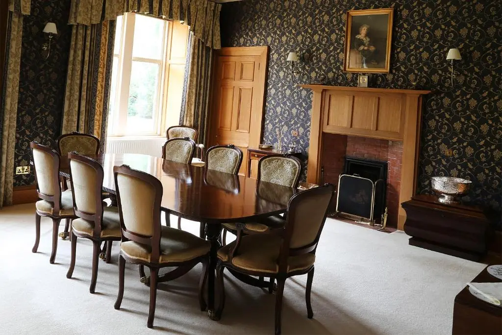 a dining room with a table and chairs and a fireplace at Carnach House in Nairn