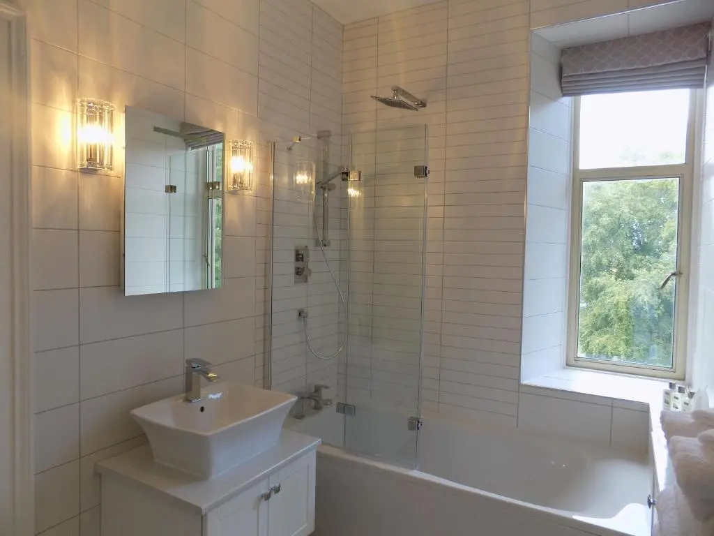 a bathroom with a sink and a tub and a mirror at Carnach House in Nairn