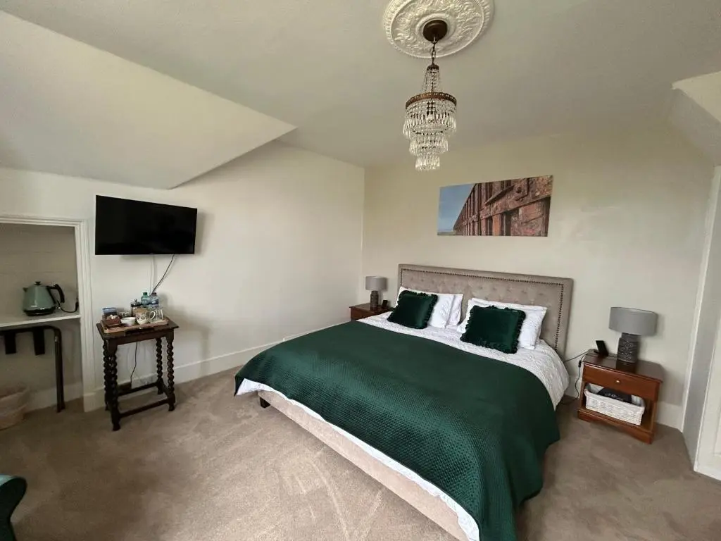 a bedroom with a green bed with a chandelier at Glen Lyon Lodge Bed and Breakfast in Nairn