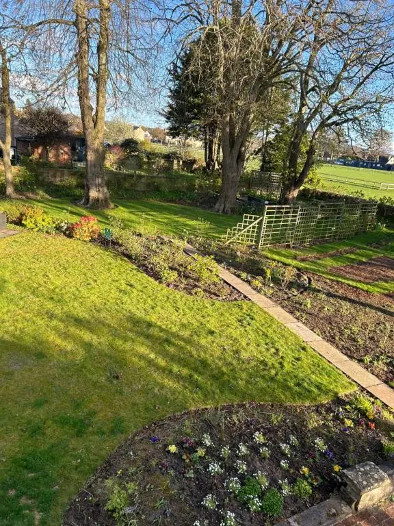 a garden with flowers and a fence and trees at Glen Lyon Lodge Bed and Breakfast in Nairn