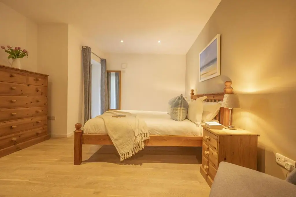 a bedroom with a bed and a dresser with a lamp at The Neuk in Kincraig