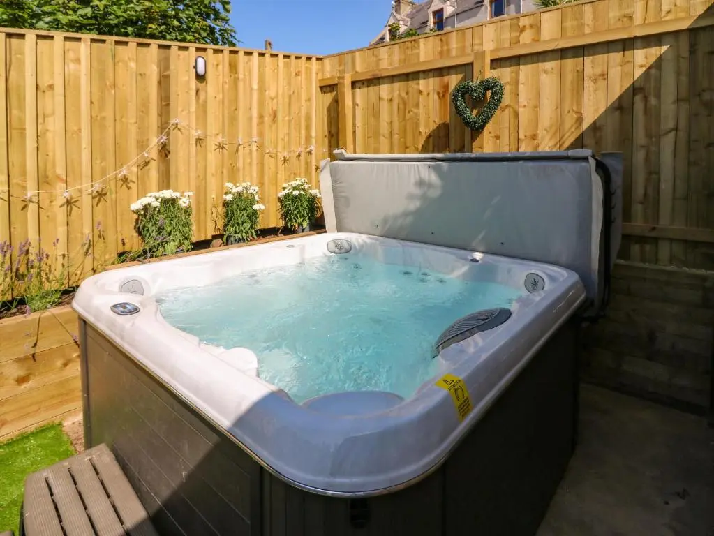 a hot tub in a backyard with a wooden fence at 111A Main Street in Banff