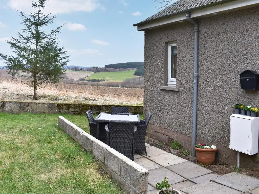 a table and chairs sitting outside of a house at Muir Cottage - Uk44788 in Bridge of Alford