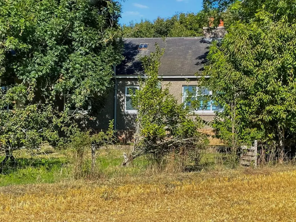 a house sitting in the middle of a field at Muir Cottage - Uk44788 in Bridge of Alford