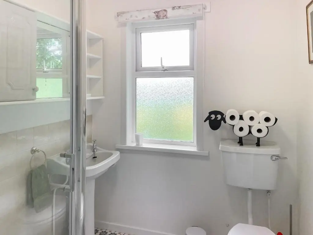 a bathroom with a toilet and a sink and a window at Muir Cottage - Uk44788 in Bridge of Alford