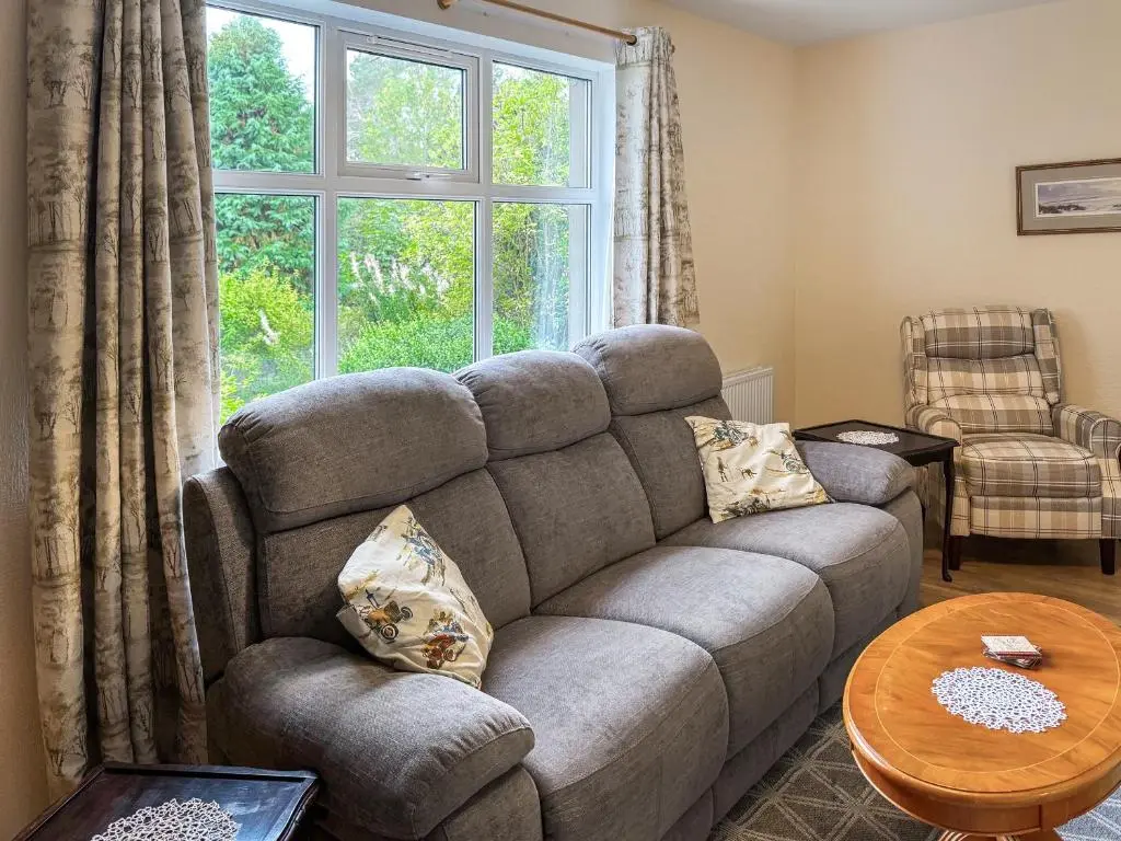 a living room with a couch and a window at Damil Cottage - Uk44789 in Bridge of Alford