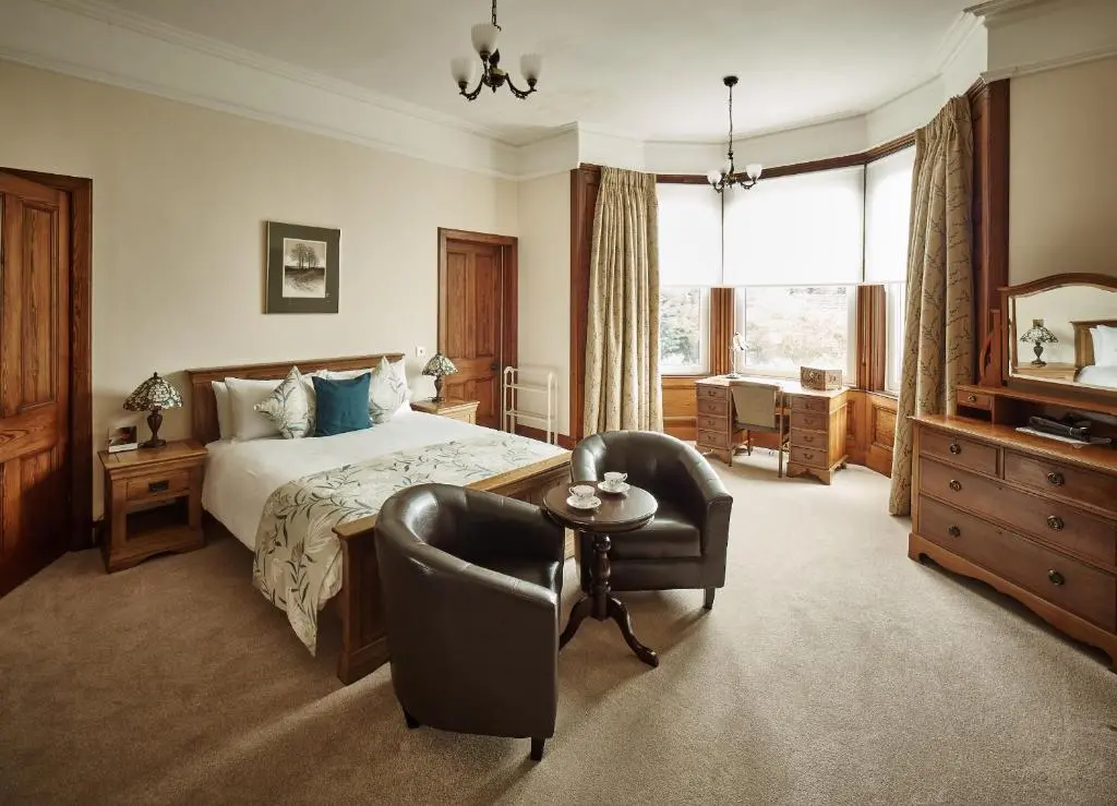 a bedroom with a bed and a chair and a table at Tali Ayer in Nairn