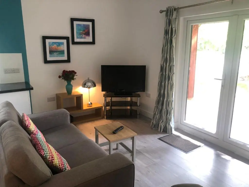 a living room with a couch and a television at The South Cabin at Easter Arr in Nairn