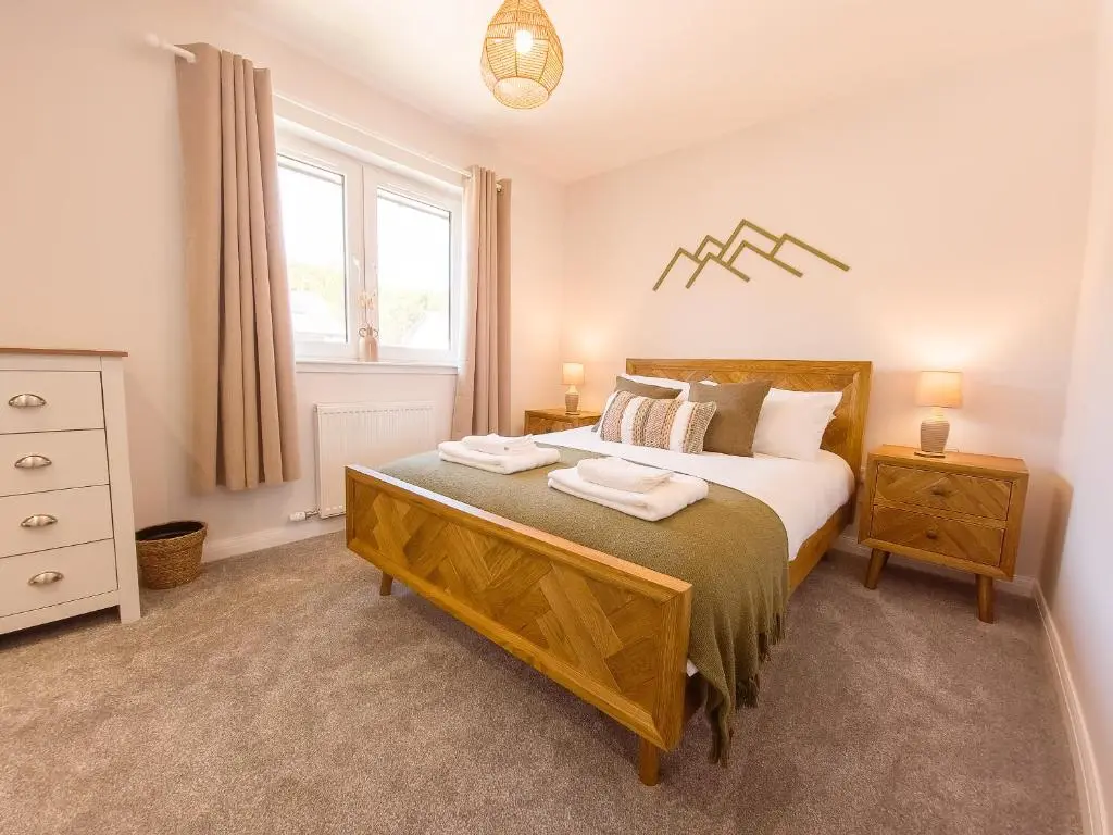 a bedroom with a bed and a dresser and a window at 4 Ben Avon in Aviemore