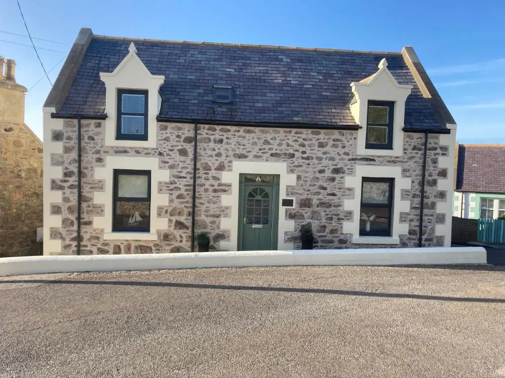 a stone house with a green door on a street at Seafront holiday home in Findochty in Findochty