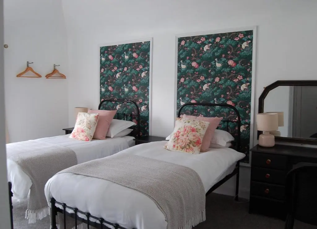 two beds in a room with floral wallpaper at Room Only Corbies Rest in Inverness