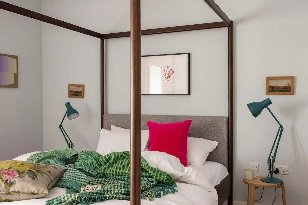 a bedroom with a canopy bed with a red pillow at The Corner House in Banchory