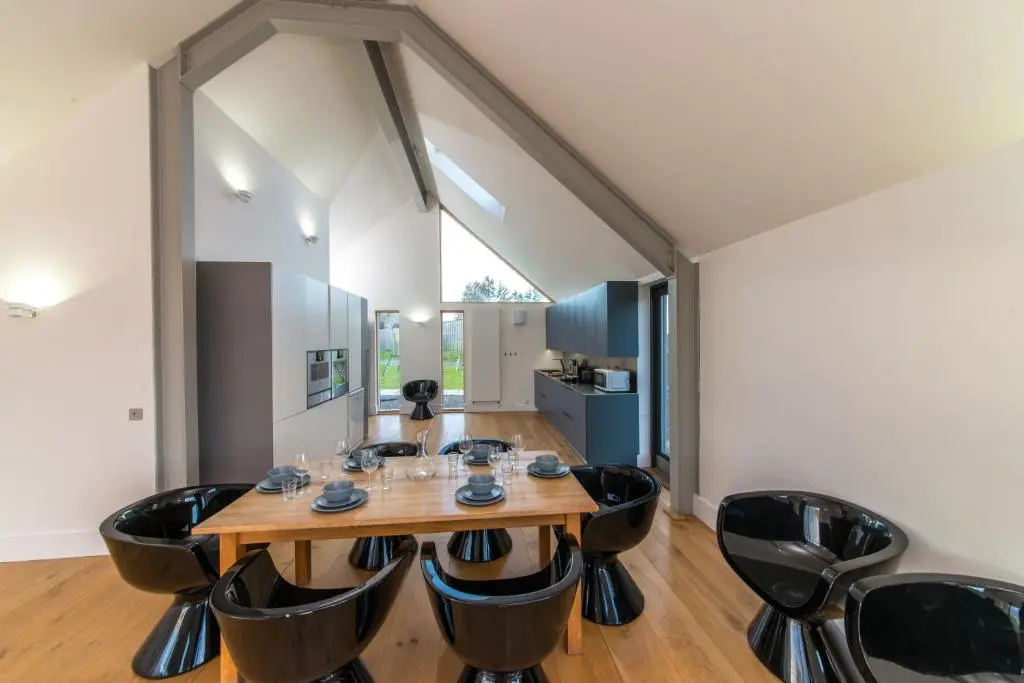 a dining room with a wooden table and black chairs at The Den, Architect Designed Barn, Beautiful Location in Kirkton of Skene