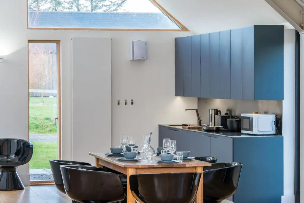 a dining room with a table and chairs and a kitchen at The Den, Architect Designed Barn, Beautiful Location in Kirkton of Skene