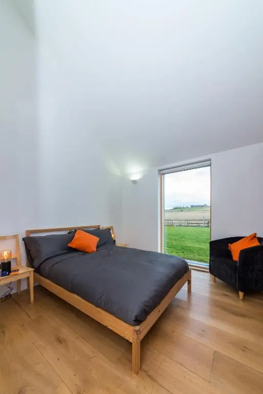 a bedroom with a large bed and a window at The Den, Architect Designed Barn, Beautiful Location in Kirkton of Skene