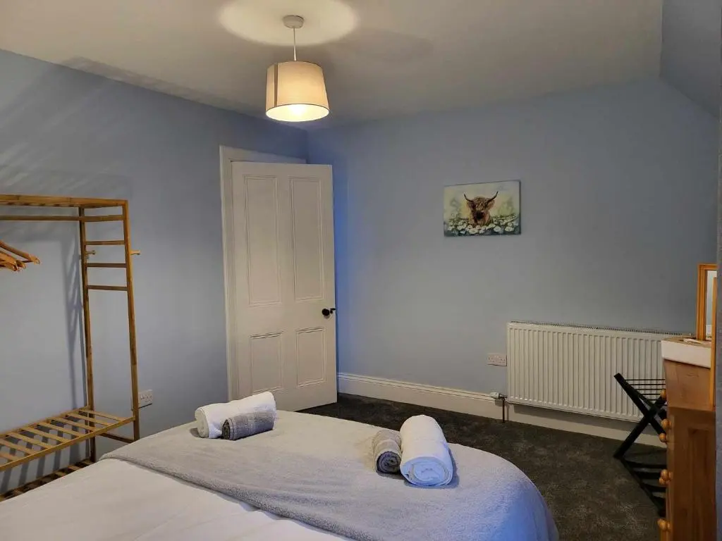 a bedroom with blue walls and a bed with towels at 16 Northcote Street, Wick in Wick