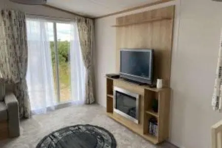 a living room with a television and a fireplace at Silver sands holiday park in Lossiemouth