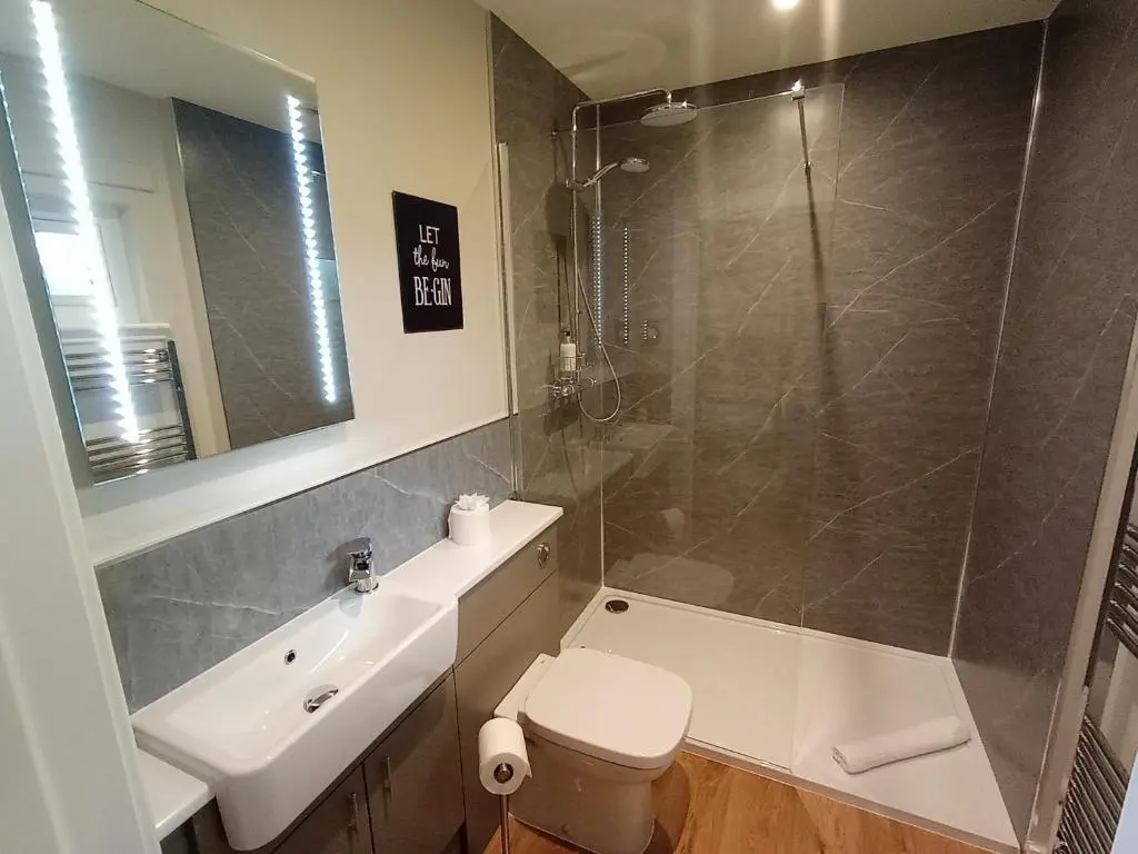 a bathroom with a shower and a toilet and a sink at Breckland Lodge 1 with Hot Tub in Belladrum