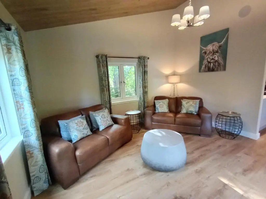 a living room with two leather couches and a table at Breckland Lodge 1 with Hot Tub in Belladrum