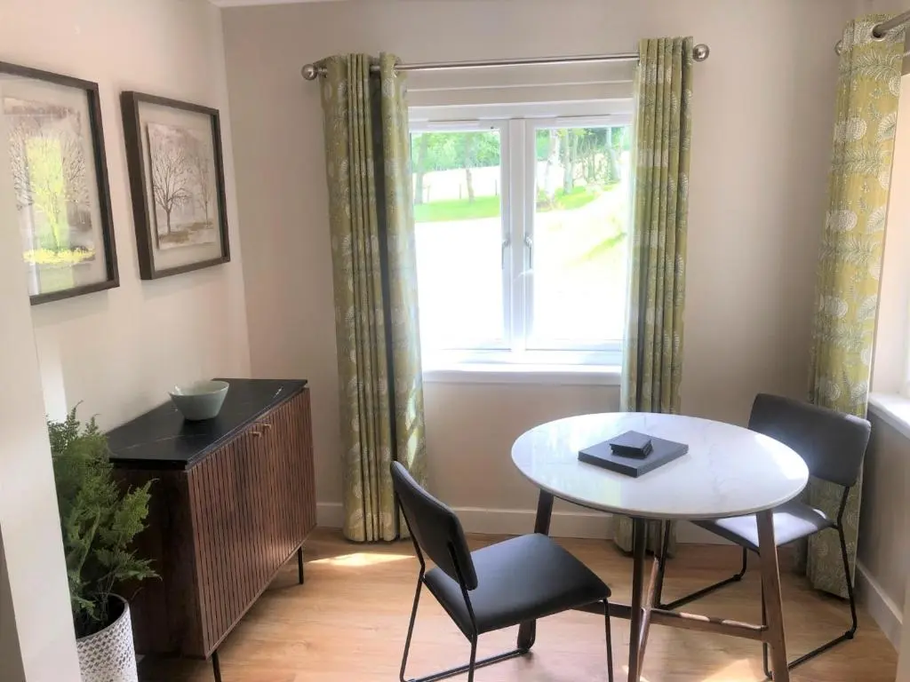 a dining room with a table and chairs and a window at Breckland Lodge 2 with Hot Tub in Belladrum