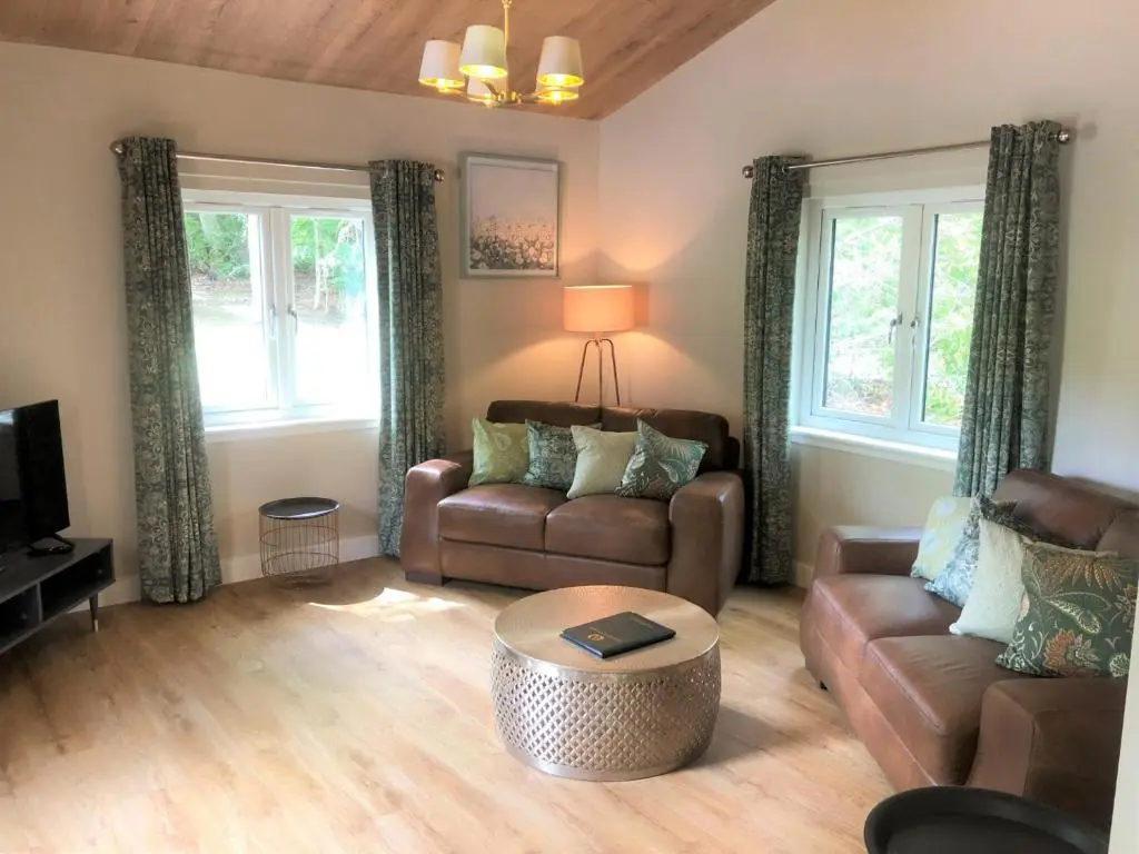 a living room with two couches and a coffee table at Breckland Lodge 2 with Hot Tub in Belladrum