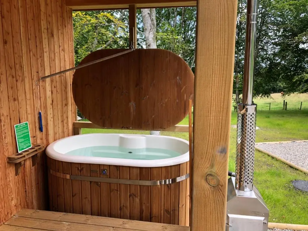 a wooden bath tub in a wooden house at Breckland Lodge 2 with Hot Tub in Belladrum