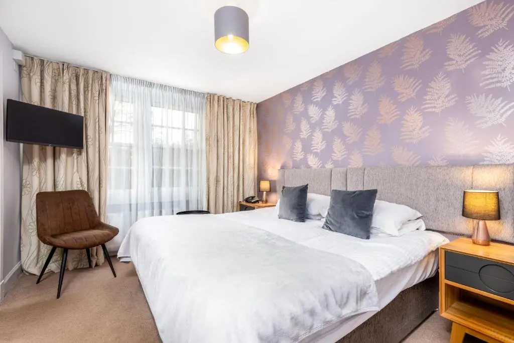 a bedroom with a large bed and a chair at Dornoch Castle Hotel in Dornoch