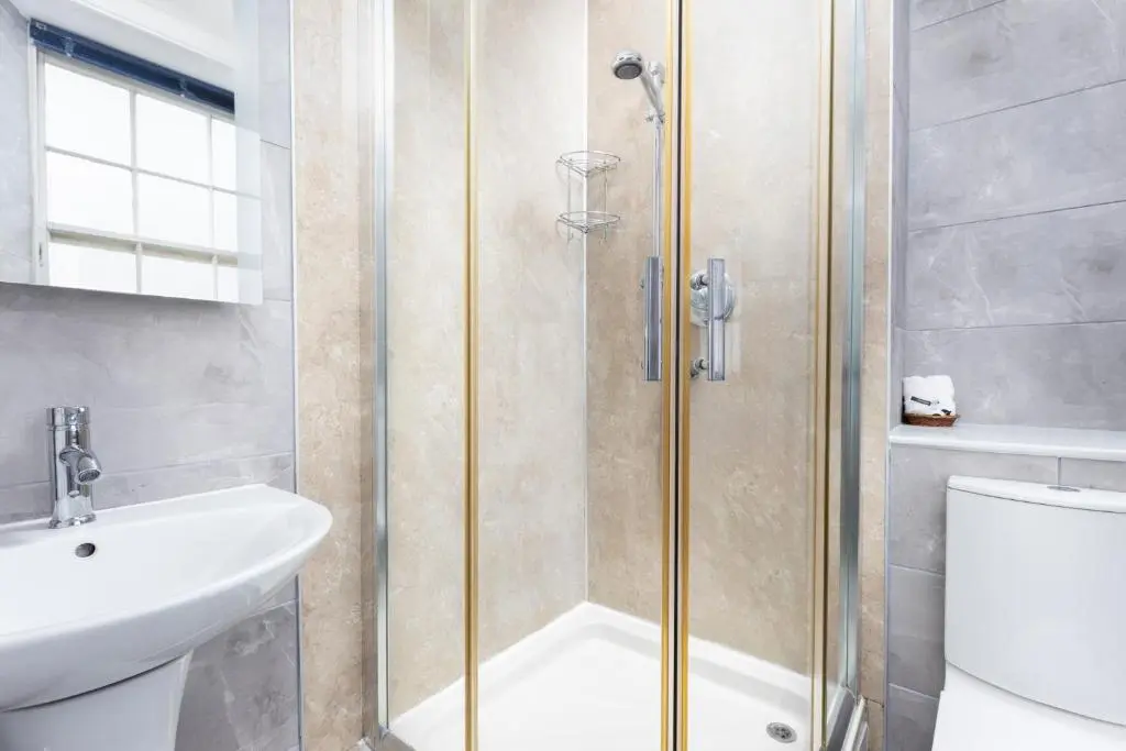a bathroom with a shower with a sink and a toilet at Dornoch Castle Hotel in Dornoch